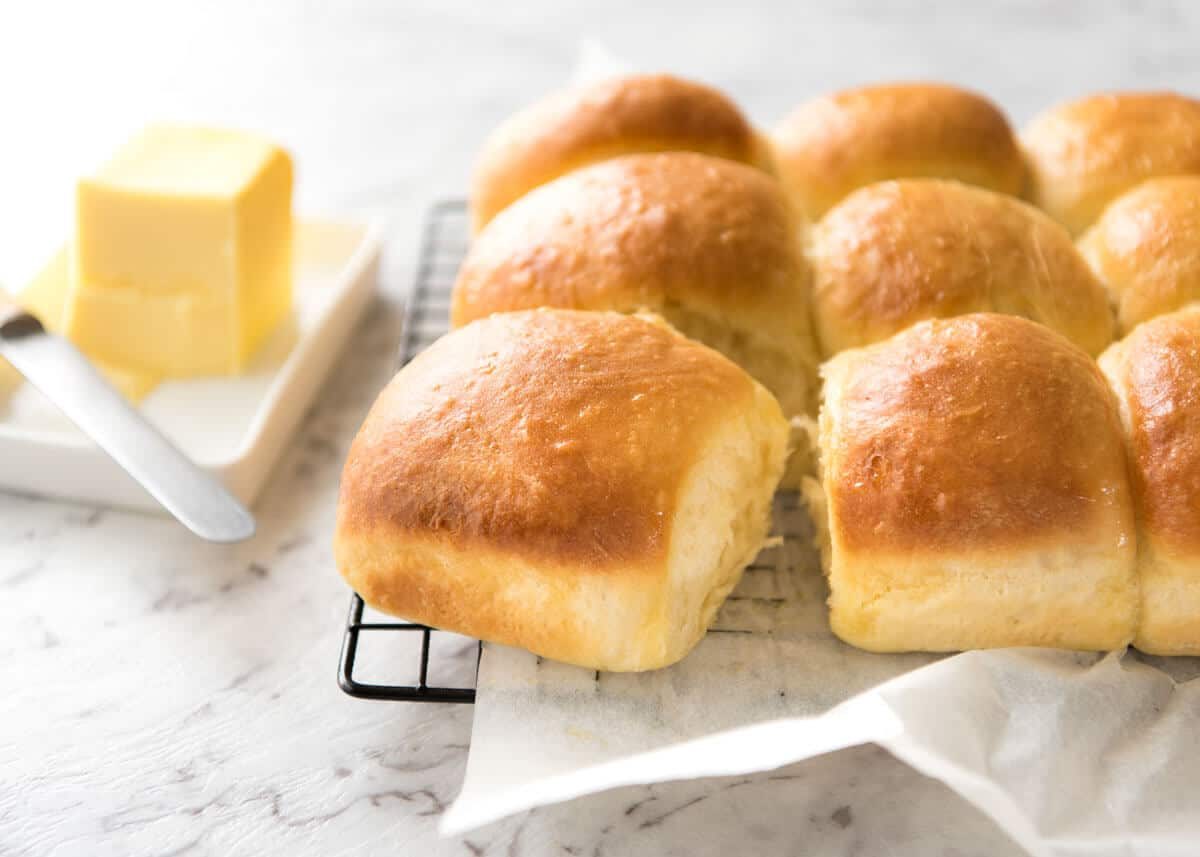 Soft no knead dinner rolls on a rack, fresh out of the oven, ready to be eaten.
